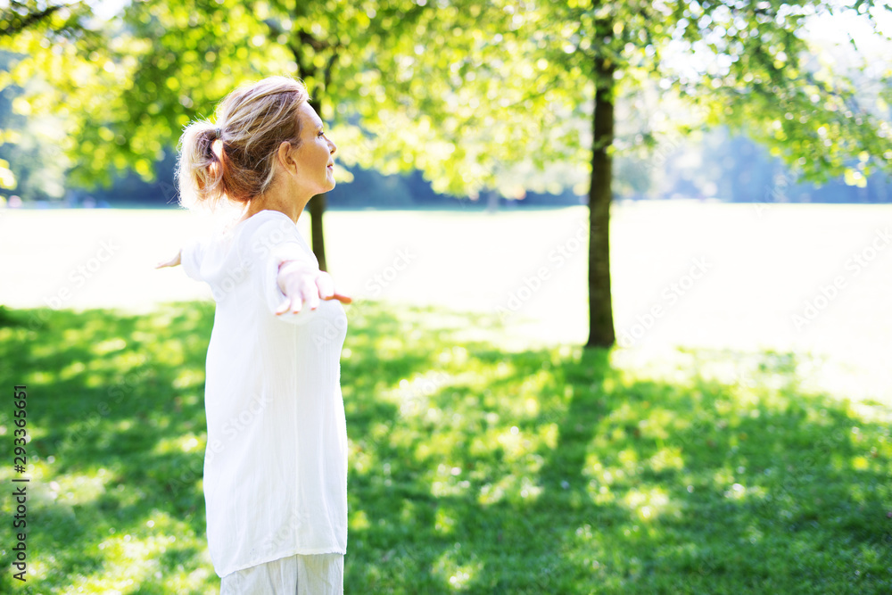 Eine attraktive Best-Ager Frau macht Meditations-Übungen im Park Eine attraktive Best-Ager Frau macht Meditations-Übungen im Park