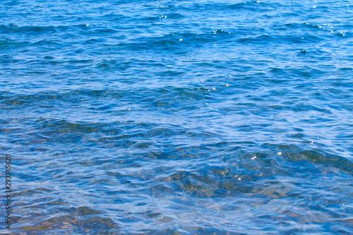 Clear water texture in blue and orange. Background of the ocean and the sea backlit by the sun. Soft waves. Natural water