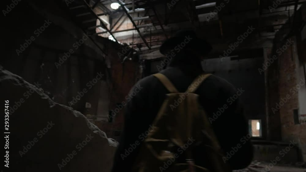 Man in a hat and coat walks through the ruined dark building Man in a hat and coat walks through the ruined dark building