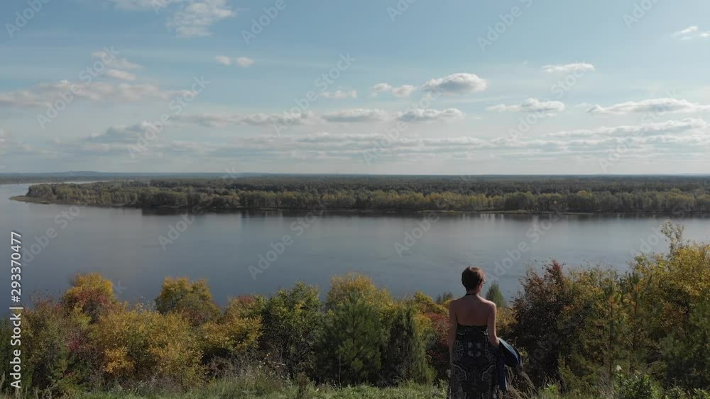 Autumn forest with a river and a girl standing on the banks of the river. View from above. Quadcopter flies next to the girl and flies to the river Autumn forest with a river and a girl standing on the banks of the river. View from above. Quadcopter flies next to the girl and flies to the river
