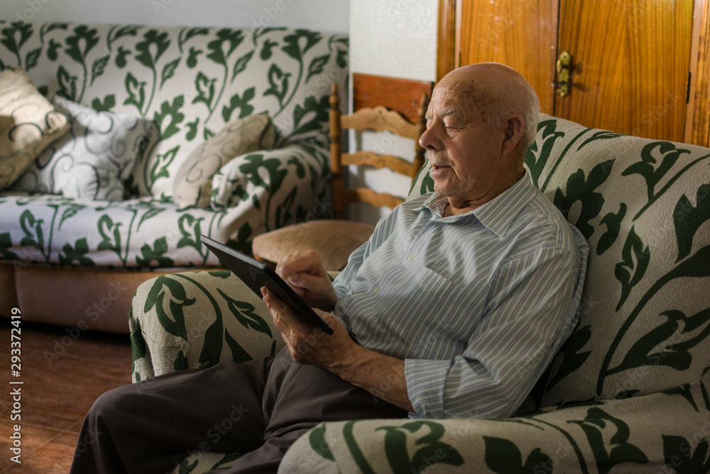 Elderly man is using a digital tablet at home Elderly man is using a digital tablet at home