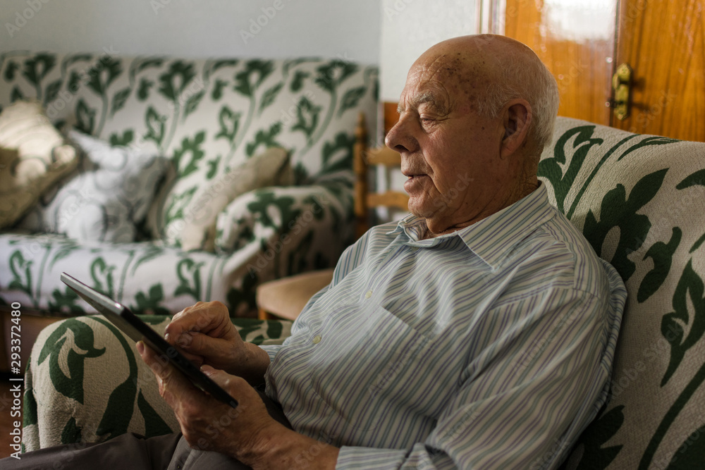 Elderly man is using a digital tablet at home Elderly man is using a digital tablet at home