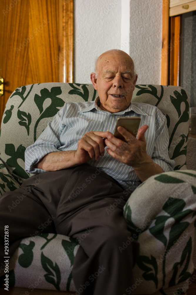 Elderly man is using his smartphone at home