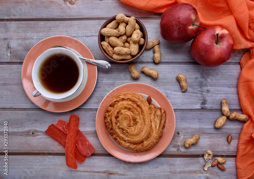 Rustic. Sweet bun. Cup of tea. Peanuts. Red apples. Wood background. Nuts. Fall. Autumnal still life. Top view.