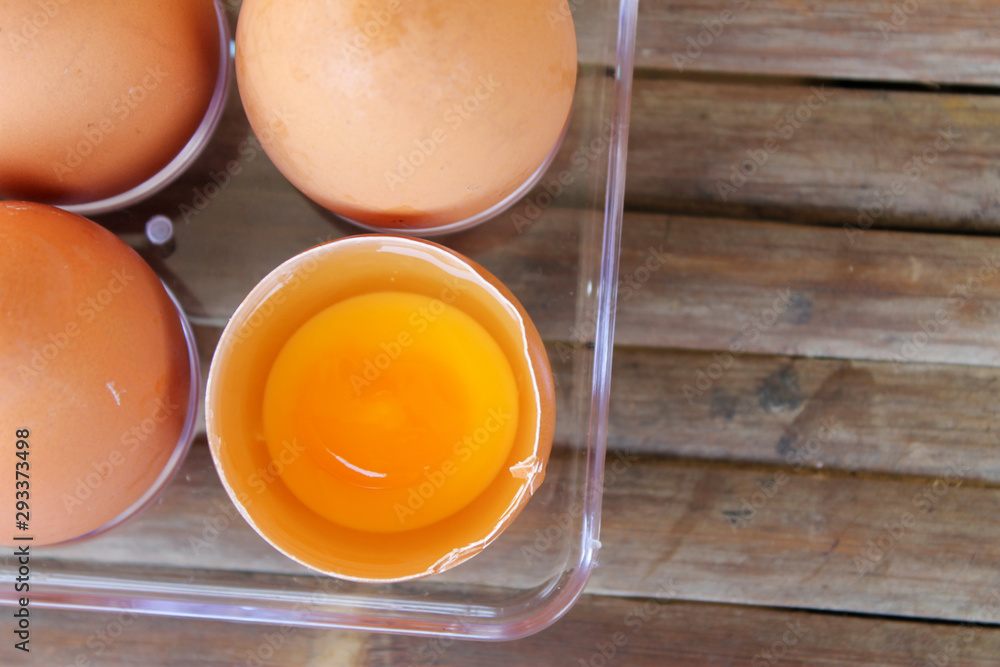 top view of broken eggshell with yellow yolk near eggs in plastic box top view of broken eggshell with yellow yolk near eggs in plastic box