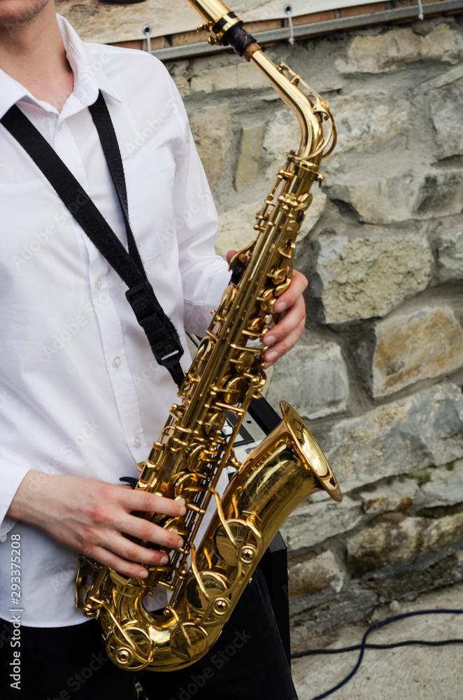 Obraz premium Closeup of a musical saxophone held in hands