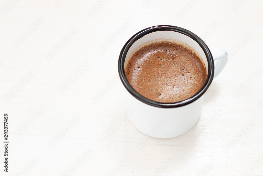 freshly brewed coffee in a white metal mug on a white table freshly brewed coffee in a white metal mug on a white table