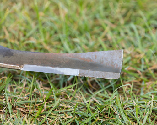 Photography Closeup of lawn mower blade with half of cutting edge sharp and other half dull with nicks
