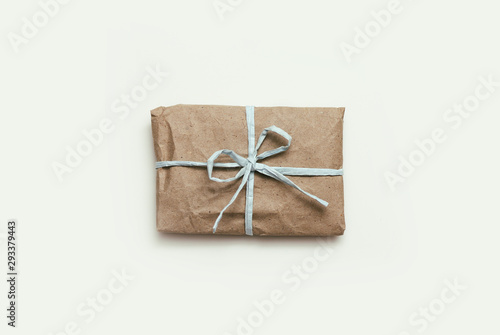 Parcel wrapping in brown craft paper and tie blue ribbon. Package. Delivery service. Online shopping. Your purchase. Gift box on a table. Isolation on white. 