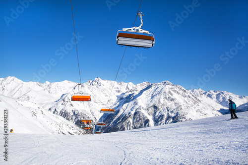 Ski lifts in the Alp mountains, Tirol, Austria. Bright blue sky and mountain covered with snow. 