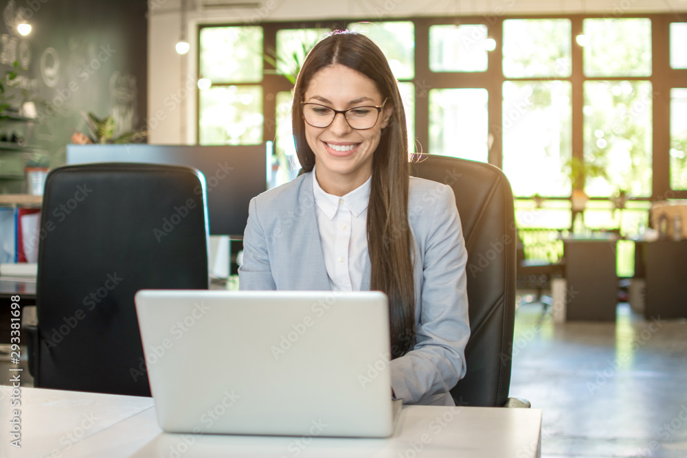Beautiful young business woman using laptop in office