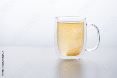 glass thermo mug of water-soluble effervescent orange tablet on a white background