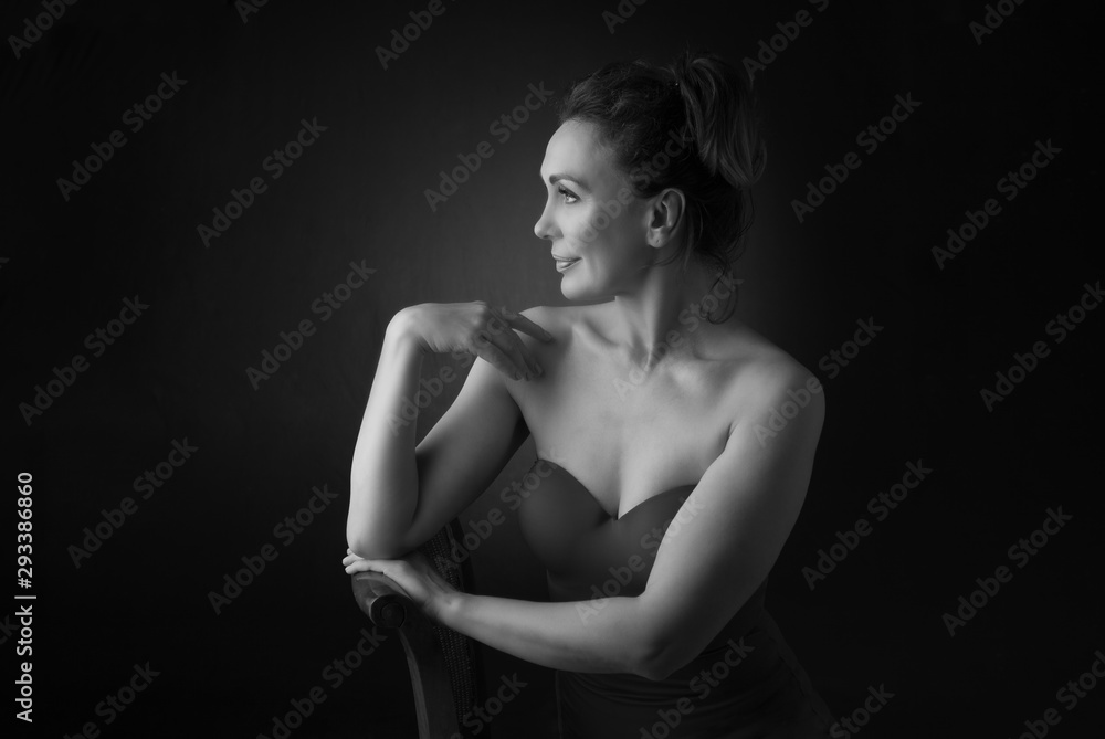 Portrait of a sensual fifty year old woman on grey studio background. Monochrome shot. Portrait of a sensual fifty year old woman on grey studio background. Monochrome shot.