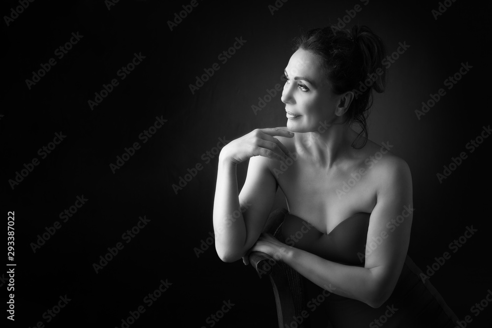 Portrait of a sensual fifty year old woman on grey studio background. Monochrome shot. Portrait of a sensual fifty year old woman on grey studio background. Monochrome shot.