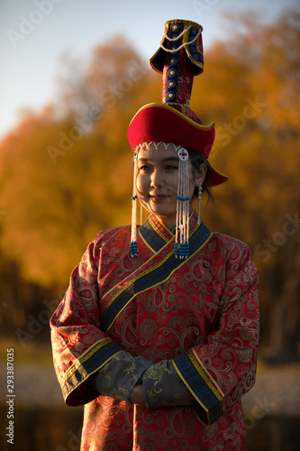 Beautiful young woman posing in traditional Mongolian dress in sunset light. Ulaanbaatar, Mongolia.