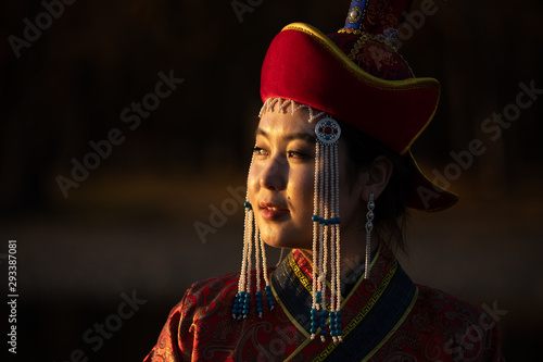 Beautiful young woman posing in traditional Mongolian dress in sunset light. Ulaanbaatar, Mongolia. photo