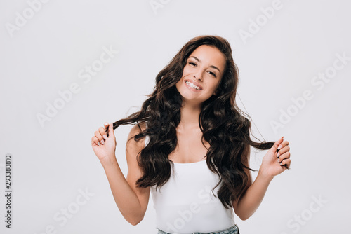 Obraz na plátně happy brunette beautiful woman with long curly healthy hair isolated on grey