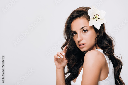 brunette beautiful woman with lily in long healthy hair isolated on grey