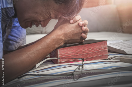 Wall Mural Close up young christian praying on old Bible, Want to help from God