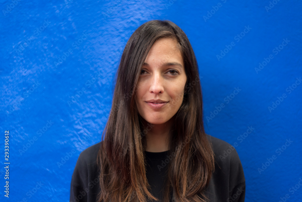 Portrait of brunette woman standing against blue wall Portrait of brunette woman standing against blue wall