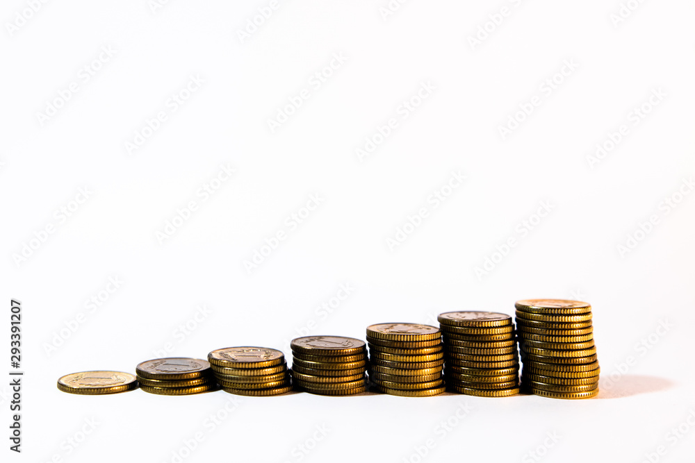 Yellow-gold coins stacked in growing piles representing steady growth of revenue isolated on white background with copy space. Background for business, banking or commerce. Yellow-gold coins stacked in growing piles representing steady growth of revenue isolated on white background with copy space. Background for business, banking or commerce.