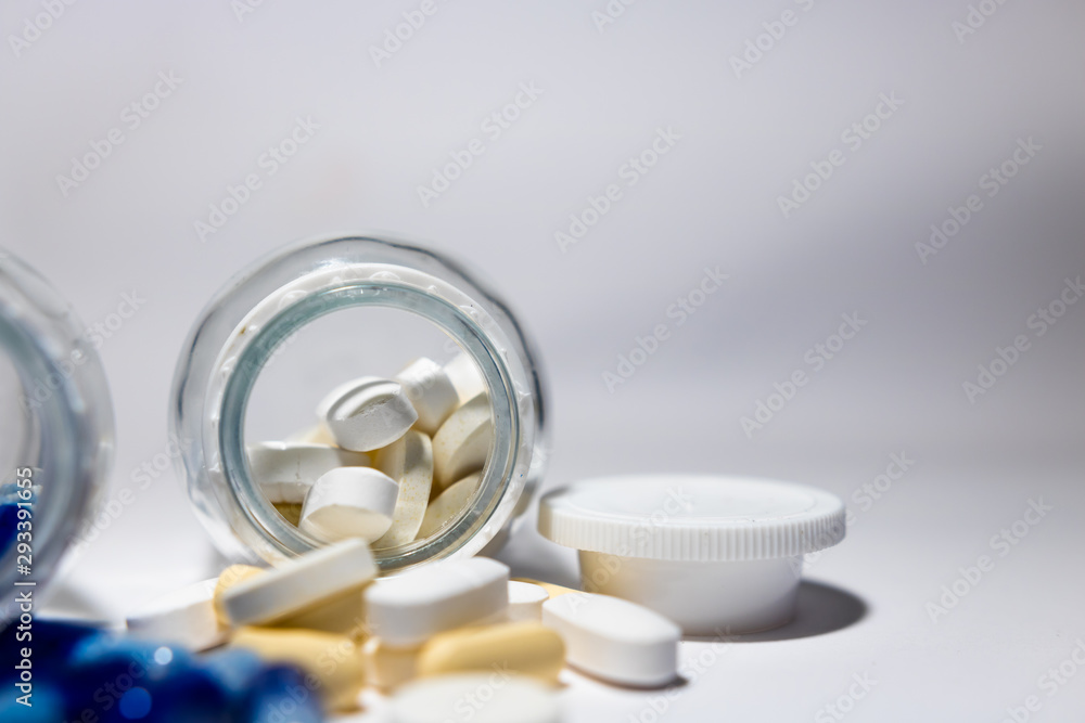 Mix of medicine pills and tablets scattered around glass bottle with some pills inside. Isolated on white background. Mix of medicine pills and tablets scattered around glass bottle with some pills inside. Isolated on white background.