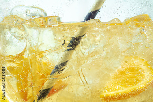 Foto Close up of lemon slices in stirring the lemonade and ice cubes on background