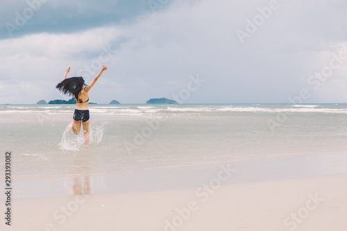 young woman walking and enjoying with water sea on the beach