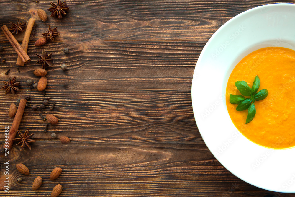 Creamy pumpkin soup with basil leaves and spices, top view. Traditional american autumn dish. Copy space. Creamy pumpkin soup with basil leaves and spices, top view. Traditional american autumn dish. Copy space.