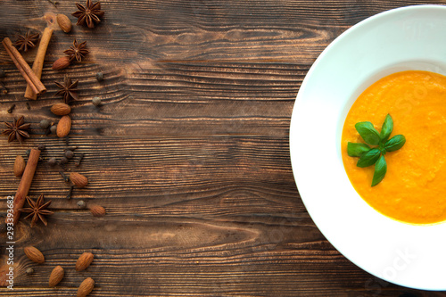 Creamy pumpkin soup with basil leaves and spices  top view. Traditional american autumn dish. Copy space. 