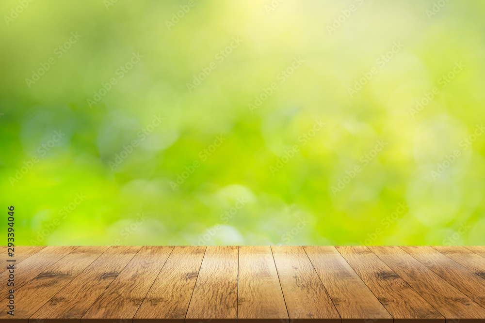 Empty wooden table in front with blur abstract green of garden.