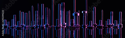 panoramic shot of diverse purple metallic screws isolated on black photo