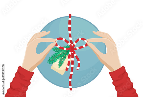 Girl packs a Christmas gift and ties a bow. Flat vector Christmas illustration.