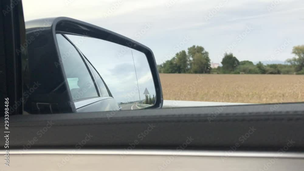 Close-up view of side mirror from vehicle on motorway. Driving a car along field. Beautiful lanscape view from car window. Car side mirror view. Highway travel. Close-up view of side mirror from vehicle on motorway. Driving a car along field. Beautiful lanscape view from car window. Car side mirror view. Highway travel.