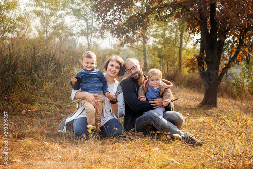 Happy family together in autumn garden/park. Parents with their two childrens take the rest in park. Outdoor in full height photo. Happy family concept