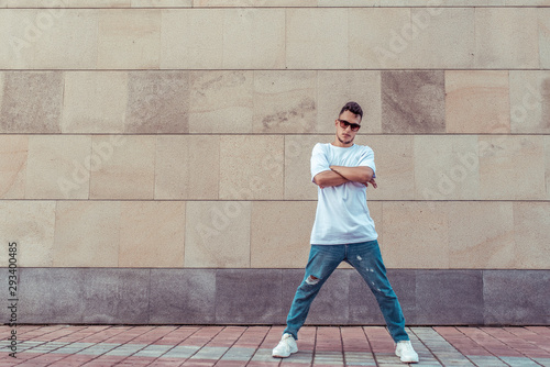 Male athlete, guy dancer in summer city. Free space for motivation text. Fashionable modern break dance style, fitness sport hip hop. Urban culture, street dance. In a t-shirt jeans and sneakers.