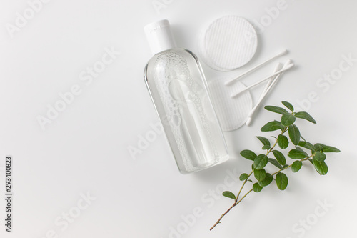 Micellar cleansing water in a bottle, cotton pads and a sprig of greenery photo