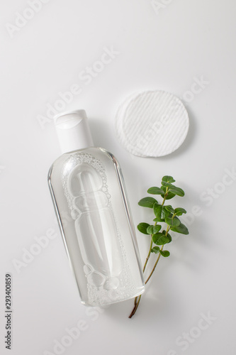 Micellar cleansing water in a bottle, cotton pads and a sprig of greenery photo