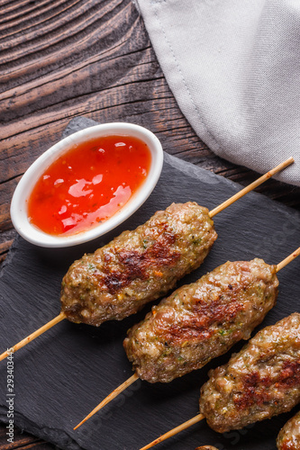 Shish kebab on the skewers with sauce on rustic table