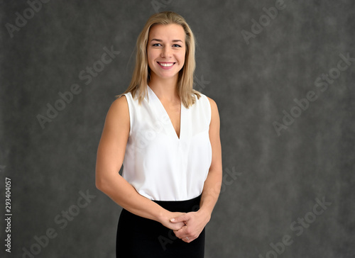 Close-up portrait of a cute caucasian blonde girl in a white blouse on a gray background. Wide smile, happiness. It is in different poses.