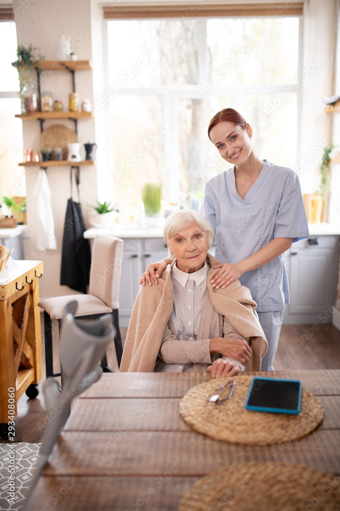 Beautiful pensioner sitting near caregiver Beautiful pensioner sitting near caregiver