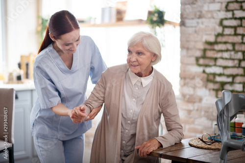 Εκτύπωση καμβά Caregiver smiling while helping aged woman to walk