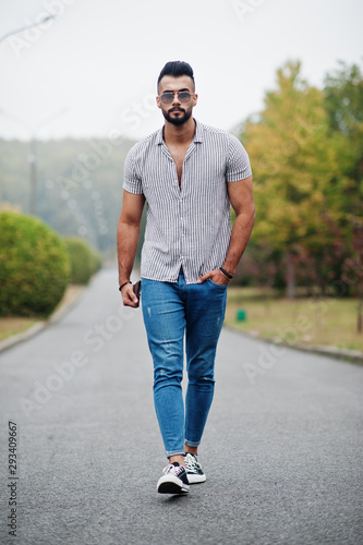 Fashionable tall arab beard man wear on shirt, jeans and sunglasses posed on park and hold wallet at hand.