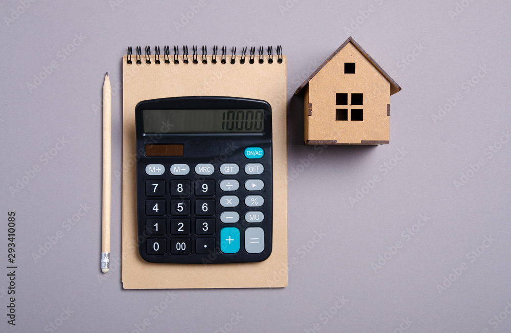 House model with brown notebook, pencil, calculator on gray background, top view House model with brown notebook, pencil, calculator on gray background, top view