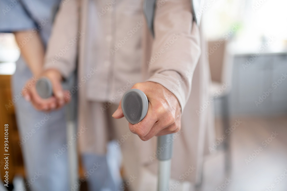 Close up of retired woman holding crutches while walking Close up of retired woman holding crutches while walking