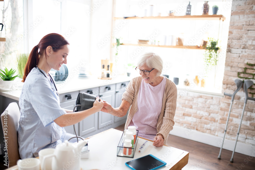 Fototapeta premium Nurse measuring blood pressure for retired lady