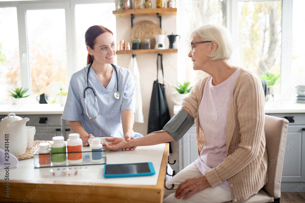 Pensioner wearing glasses speaking with nurse Pensioner wearing glasses speaking with nurse