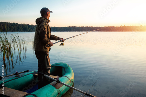 Male fisherman at dawn on the lake catches a fishing rod. Fishing hobby vacation concept. Copy space.