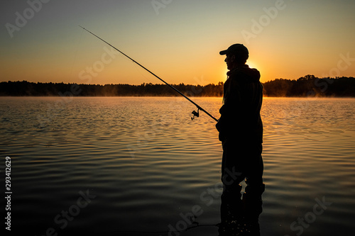 Tela Male fisherman at dawn on the lake catches a fishing rod