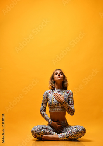 Young attractive woman practicing yoga, working out, wearing sportswear, full length on a yellow background in the studio. 